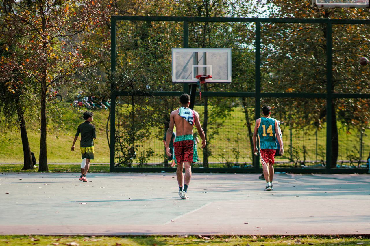Services Energetic group of teenagers playing basketball outdoors on a sunny day.